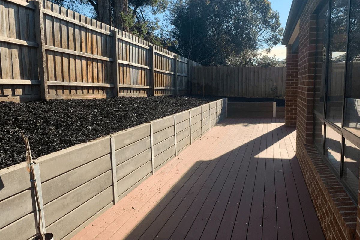 Concrete sleeper retaining wall along a fence line